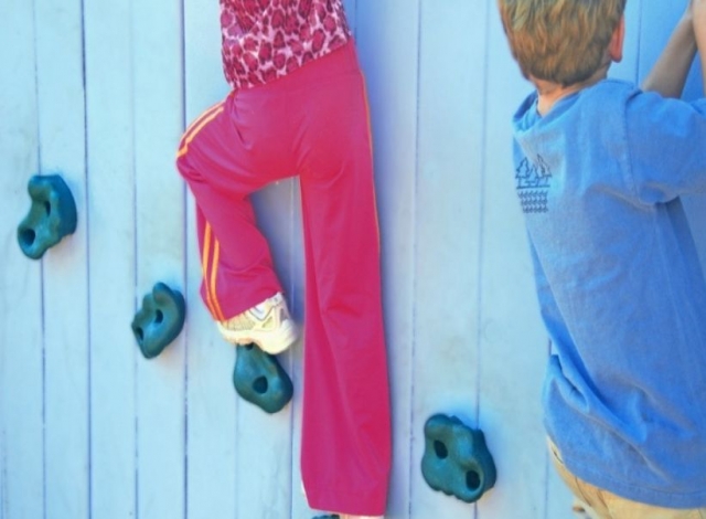  two children climbing an artificial climbing wall 
